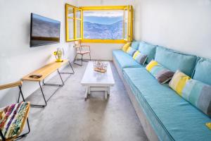 a living room with a blue couch and a table at Serifos 1890 cliff house in Serifos Chora