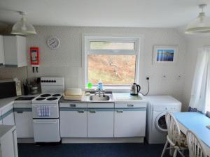 a kitchen with a sink and a stove and a window at Tigh-na-Mara in Lochinver