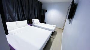 two beds in a small room with black curtains at SMART HOTEL SEKSYEN 15 SHAH ALAM in Shah Alam