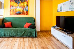 sala de estar con sofá verde y TV en Casa Cobo Exclusivo Alojamiento en Madrid, en Madrid
