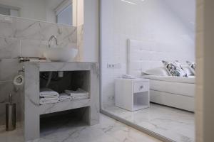 biała łazienka z umywalką i łóżkiem w obiekcie Patio di Fiori w mieście Łuck