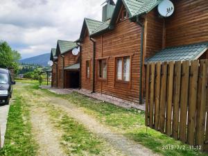 a row of wooden houses on a dirt road at Котедж ,,ТІК" in Tatariv