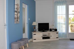 a living room with a television on a cabinet with stools at Maison pour 6 au coeur de Saint-Hilaire-de-Riez in Saint-Hilaire-de-Riez