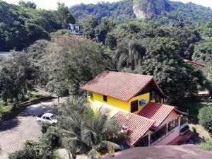 a yellow house with a car parked in front of it at Chalé em Mangaratiba - 5 min. da Praia e da Balsa. in Mangaratiba