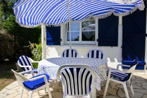 a blue and white table with chairs and an umbrella at Maison pour 6 au coeur de Saint-Hilaire-de-Riez in Saint-Hilaire-de-Riez