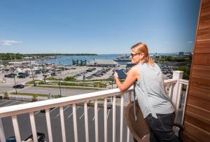 a woman standing on a balcony looking at the water at Rockland Harbor Hotel in Rockland