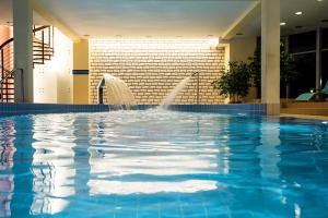 a swimming pool with a fountain in a building at Sanatorium Uzdrowiskowe LECH in Kołobrzeg