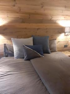 a bed with white pillows and a wooden wall at Agriroom in Rumo