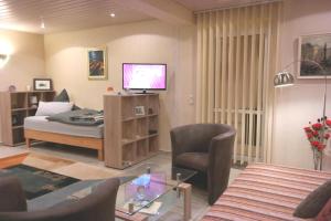 a living room with a bed and a chair and a television at APPartementWESTiNGhaus in Edemissen