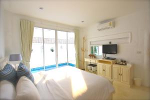 a bedroom with a white bed and a television at Costa Village Pool Villa in Jomtien Beach
