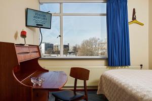 a hotel room with a piano and a bed and a window at Pension Homeland in Amsterdam
