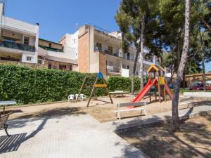 a playground with swings and benches in front of a building at Sol & Relax en centro, Sitges. in Sitges