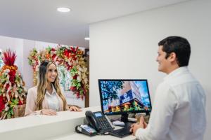 um homem a falar com uma mulher em frente a um computador em Ambar Hotel Boutique em Cali