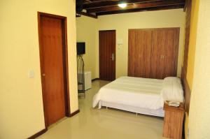 Un dormitorio con una cama blanca y una puerta de madera. en Hotel da Montanha, en Miguel Pereira 35 fotos más