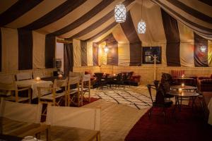 a dining room with tables and chairs in a tent at Bivouac de luxe Mhamid in Mhamid