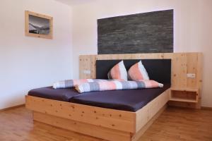 uma cama de madeira com almofadas num quarto em Haus Gastl em Arzl im Pitztal
