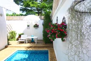 a patio with a swimming pool and flowers at Costa Village Pool Villa in Jomtien Beach