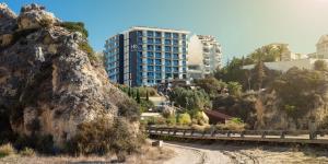 un bâtiment situé sur le côté d'une montagne à côté d'une route dans l'établissement RR Hotel da Rocha, à Portimão