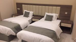 a bedroom with two beds and two night stands at نيلوفر للشقق المخدومة in Yanbu
