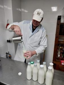 a man in a kitchen pouring milk into bottles at Betsie`s Place in Großsander