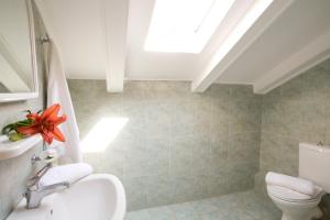 a bathroom with a toilet and a sink and a skylight at Pansion Filoxenia Apartments & Studios in Tsoukalades