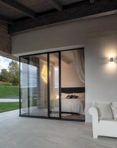 Dormitorio con puertas de cristal y cama. en La Maggiolina Country House, en Montelabbate