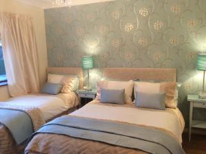 two beds in a room with wallpaper and lamps at Glen na Smole in Wicklow