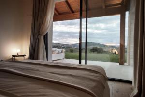 een slaapkamer met een bed en een groot raam bij La Maggiolina Country House in Montelabbate
