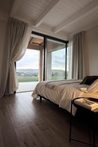 a bedroom with a bed and a large window at La Maggiolina Country House in Montelabbate