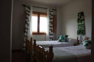 1 dormitorio con 2 camas y ventana en Apto. Rural Las Candelas. La Covatilla, en Candelario