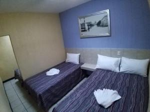 2 letti in una camera con pareti viola e cuscini bianchi di Hotel Aguila a Guadalajara