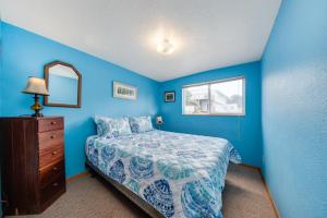 a blue bedroom with a bed and a dresser and a mirror at The Best Little Beach House on the Oregon Coast! in Lincoln Beach