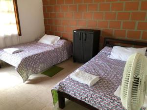 a room with two beds and a chair in it at Finca Hotel Andaquies in Armenia