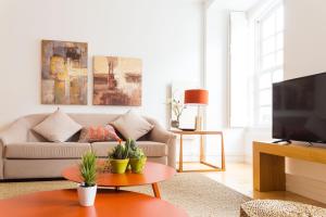 a living room with a couch and a tv at Chiado Spacious and Luxurious by Courtesy Morning in Lisbon