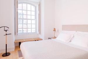 a white bedroom with a bed and a window at Chiado Spacious and Luxurious by Courtesy Morning in Lisbon