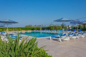 uma piscina com cadeiras azuis e guarda-sóis em Rafael Hotel-Adults Only em Lindos