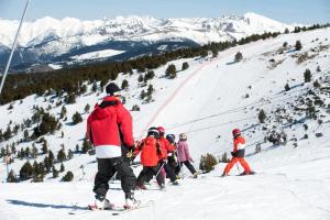 un groupe de personnes skier sur une piste enneigée dans l'établissement Apartamentos Pessets Adelaida, à Sort