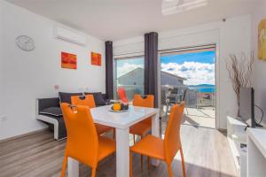 a dining room with a white table and orange chairs at Villa top of Murter, one bedroom apartment 2 in Murter