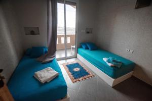 two beds in a room with a window at Agadir well in Mirleft