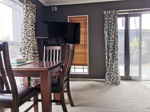 a dining room with a table and chairs and a television at Lakeview Holiday Hideaway in Taupo