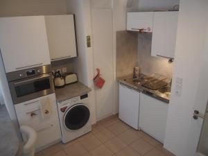 une petite cuisine avec des placards blancs et un lave-linge. dans l'établissement Le Carré des oiseaux, à Strasbourg