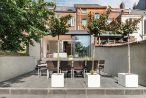 a patio with potted trees and a table and chairs at Flemishome, The Retreat For Family And Friends in Halle