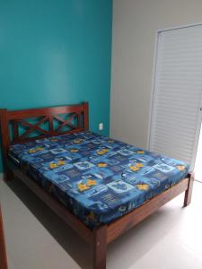 uma cama com um edredão azul num quarto em Praialar Apartamentos Ubatuba em Ubatuba