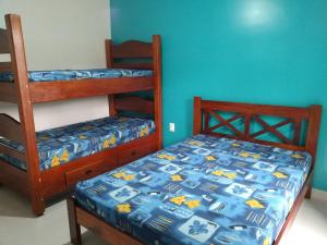 Praialar Apartamentos Ubatuba في أوباتوبا: غرفة نوم بسريرين بطابقين وجدار ازرق