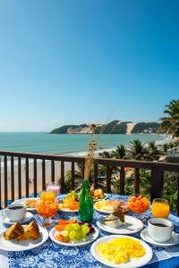 a table with plates of food on a table with the ocean at Blue Marlin Apartments in Natal