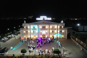 un groupe de personnes debout à l'extérieur d'un bâtiment la nuit dans l'établissement Grand Antika, à Peje