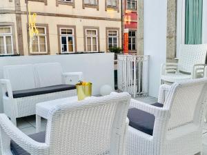 un grupo de sillas y mesas blancas en un balcón en The Arch - Charming Apartments in the Historic Center, en Braga