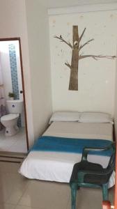 - une chambre avec un lit et un arbre sur le mur dans l'établissement Hotel Monaco De Riohacha, à Ríohacha
