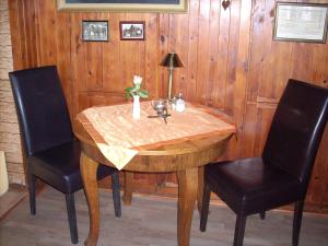 een houten tafel met twee stoelen en een vaas met bloemen erop bij Pension & Restaurant "Alte Schule" in Kluis