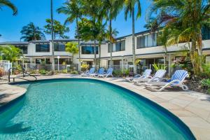 a swimming pool with chairs and a building at Noosa Place Resort in Noosaville